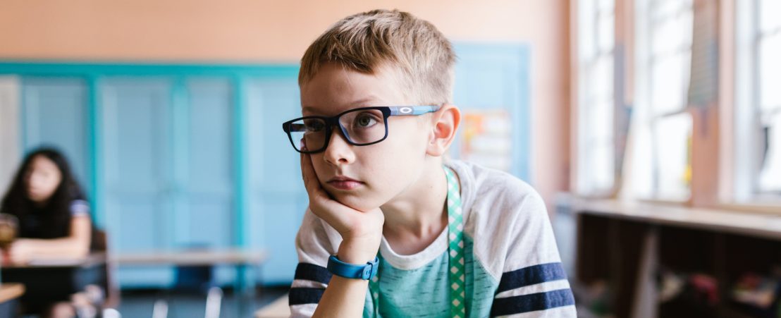 Niño en clase con miopía infantil