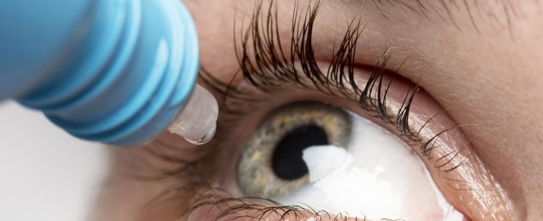 Detalle de una gota de colirio (tratamiento para la conjuntivitis) a punto de caer dentro del ojo.