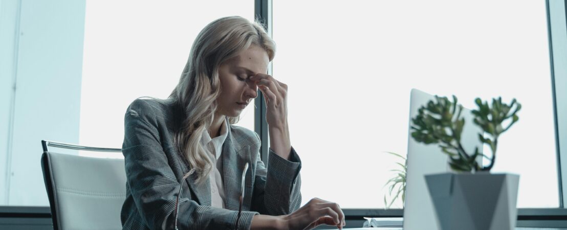 Una dona descansa al seu despatx amb els ulls tancats, davant de l'ordinador